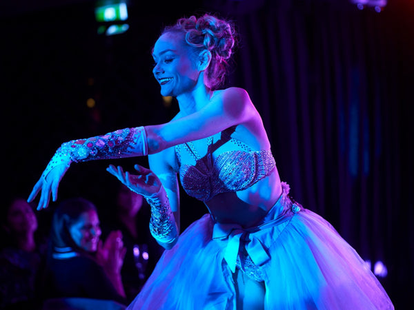 Balletic burlesque dancer in a costume with intricate details on stage under colorful lighting in a cabaret show in Potts Point.